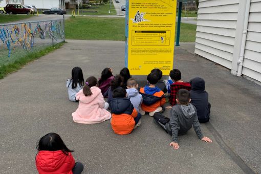 Group of children sitting in front of the yellow side of the Where Am I exhibit 