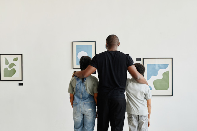 A parent and two children looking at art. 