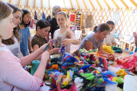 A group of young people inside a yurt making felt crafts