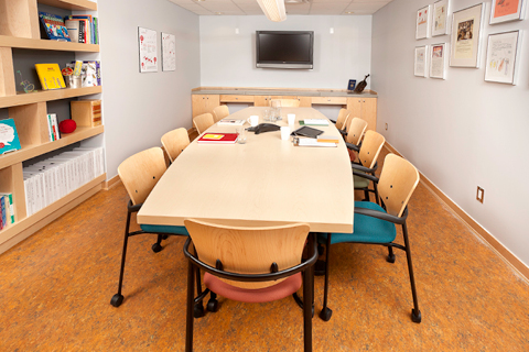 A boardroom in the ArtStarts office. On the right hand side is the ArtStarts resource bookshelf.