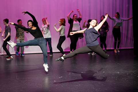 A group of young people performing on stage mid-dance