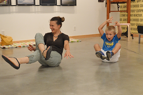 A parent and a young person sitting on a concrete floor with their limbs in motion